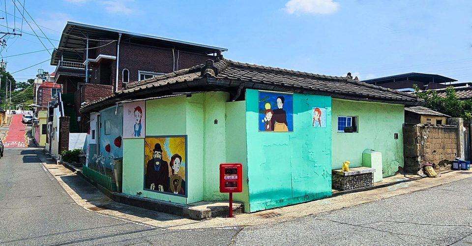 기와지붕 모퉁이 집의 민트·연두 벽에 그린 빨간머리앤 그림들과 빨간 우체통